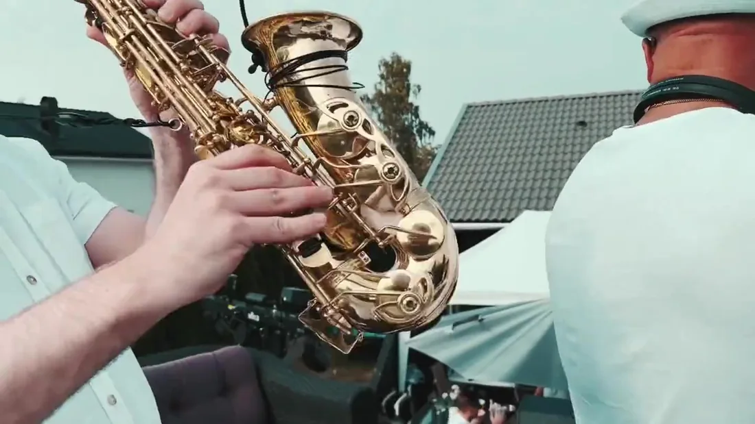 Saxofonist spelar live vid DJ-båset under en utomhusfest